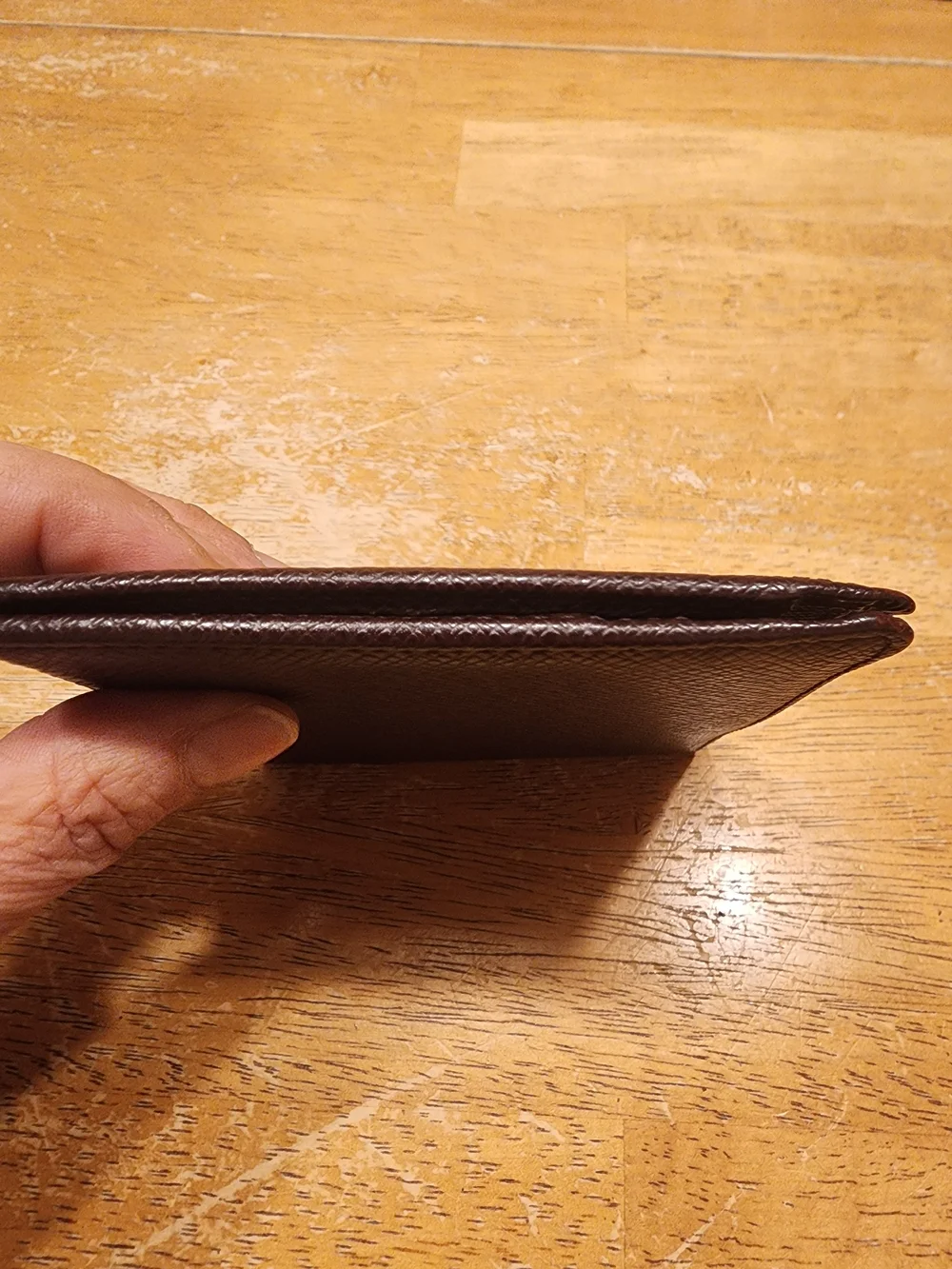 burgandy Louis Vuitton Taiga leather bifold wallet featuring a debossed LV